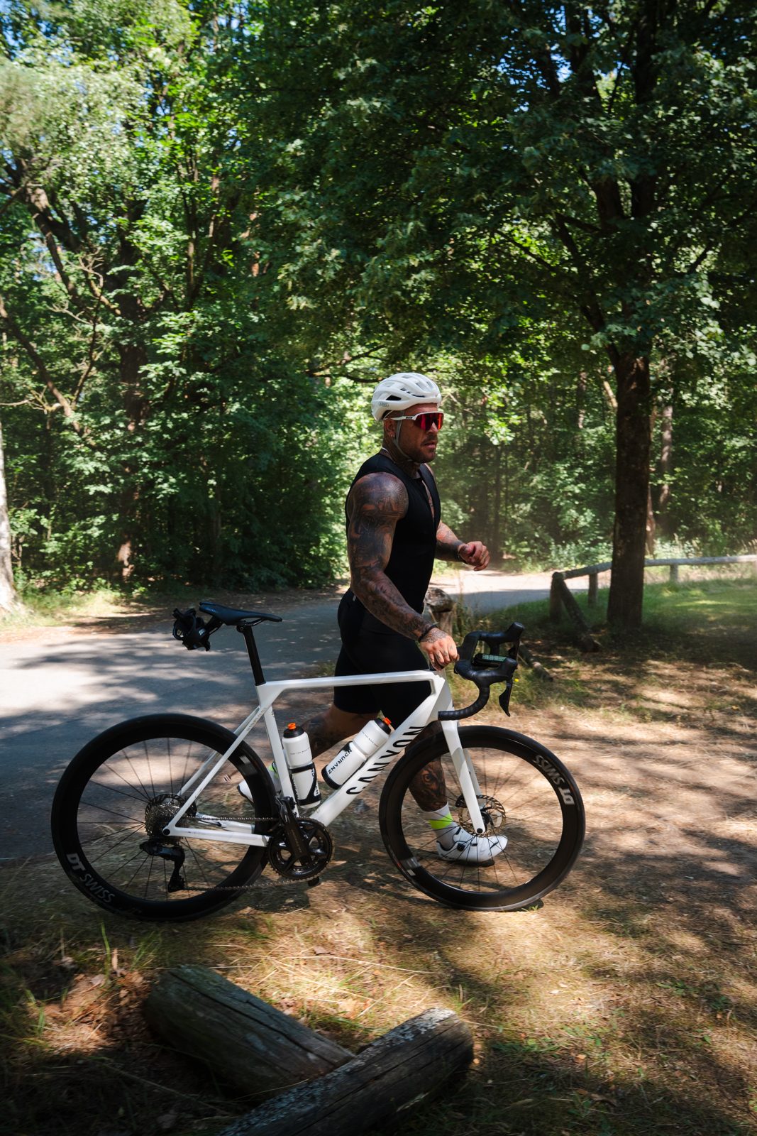 Fabian schiebt sein Rennrad durch den Wald, Tageslicht
